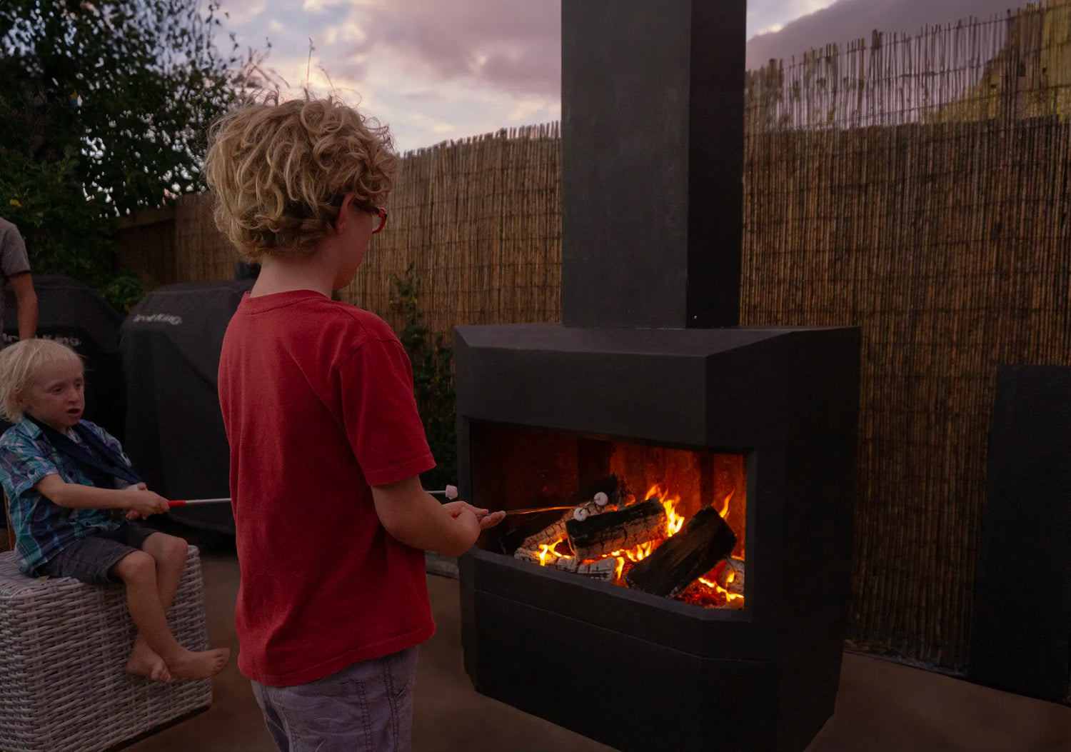 Boy with red t-shirt roasting marshmallow on Pique fireplace